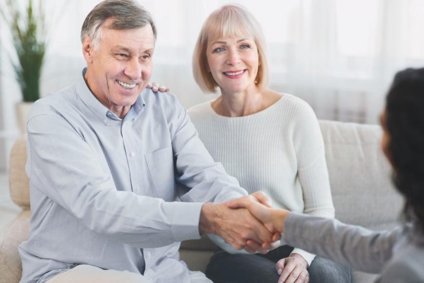 Older man with older woman, shaking hands with behavioral health care provider