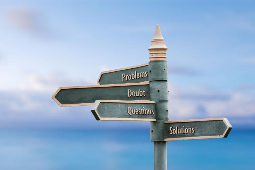 A metal pole with four signs pointing in different directions. The sign on top reads Problems, the sign below it reads Doubt, the sign below that reads Questions, and the bottom sign reads Solutions.