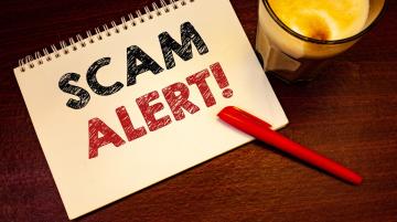 SCAM ALERT written on cover of three-ring notebook