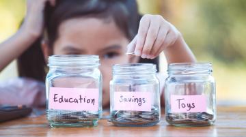 Little girl putting change in to three jars