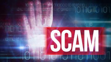 The word SCAM is in white, bold type on a dark, red background.  Behind the word is an open hand with palm facing the camera, plus strings of numbers with random ones and zeros.